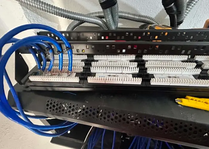 Blue Cat6 camera cable runs neatly terminated into a wall-mounted patch panel.