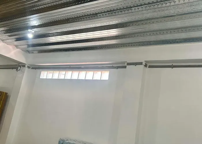 Cable trunking routed along a wall-ceiling junction in a room lined with stacked boxes, ready for camera cabling.