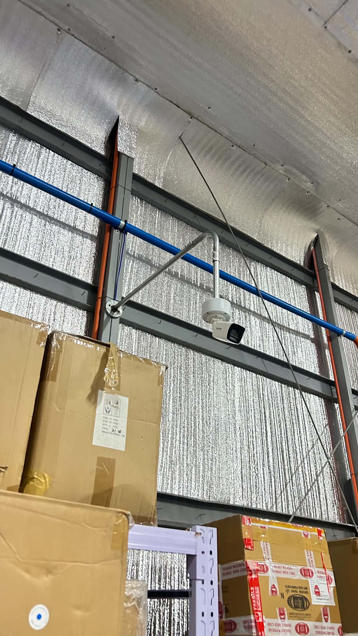 Technician working near ceiling routes above stored office materials.