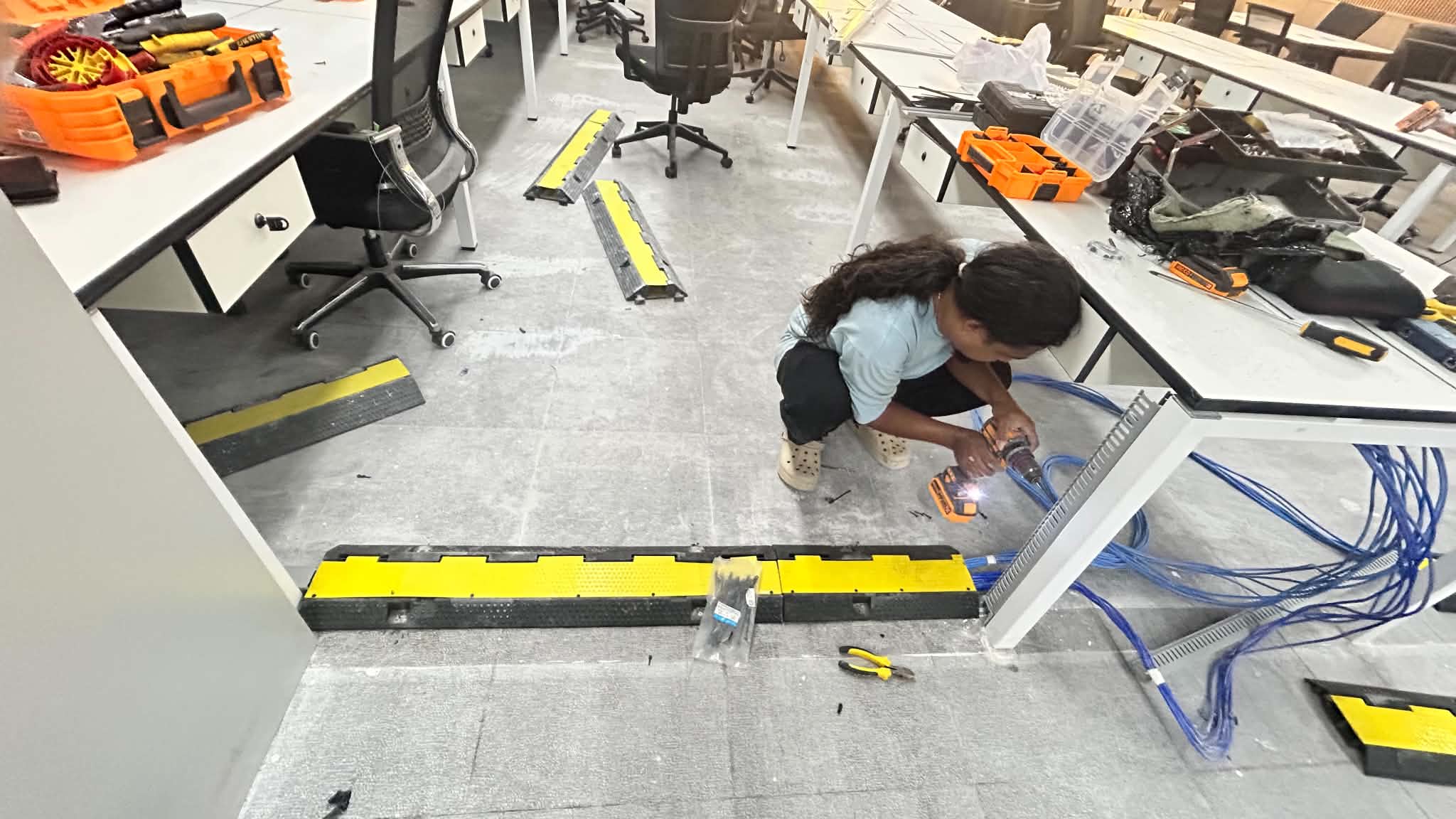 Technician measuring and preparing an office work area for installation.