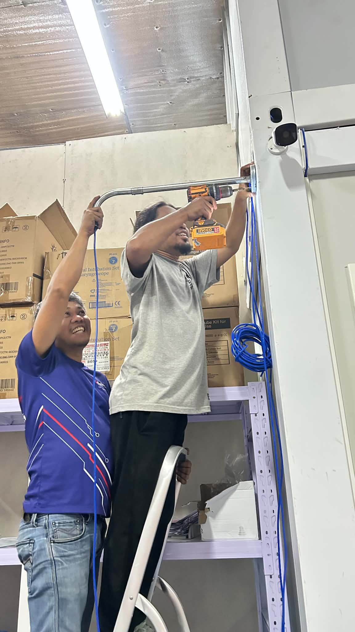 Technicians positioning and checking ceiling-mounted CCTV equipment.
