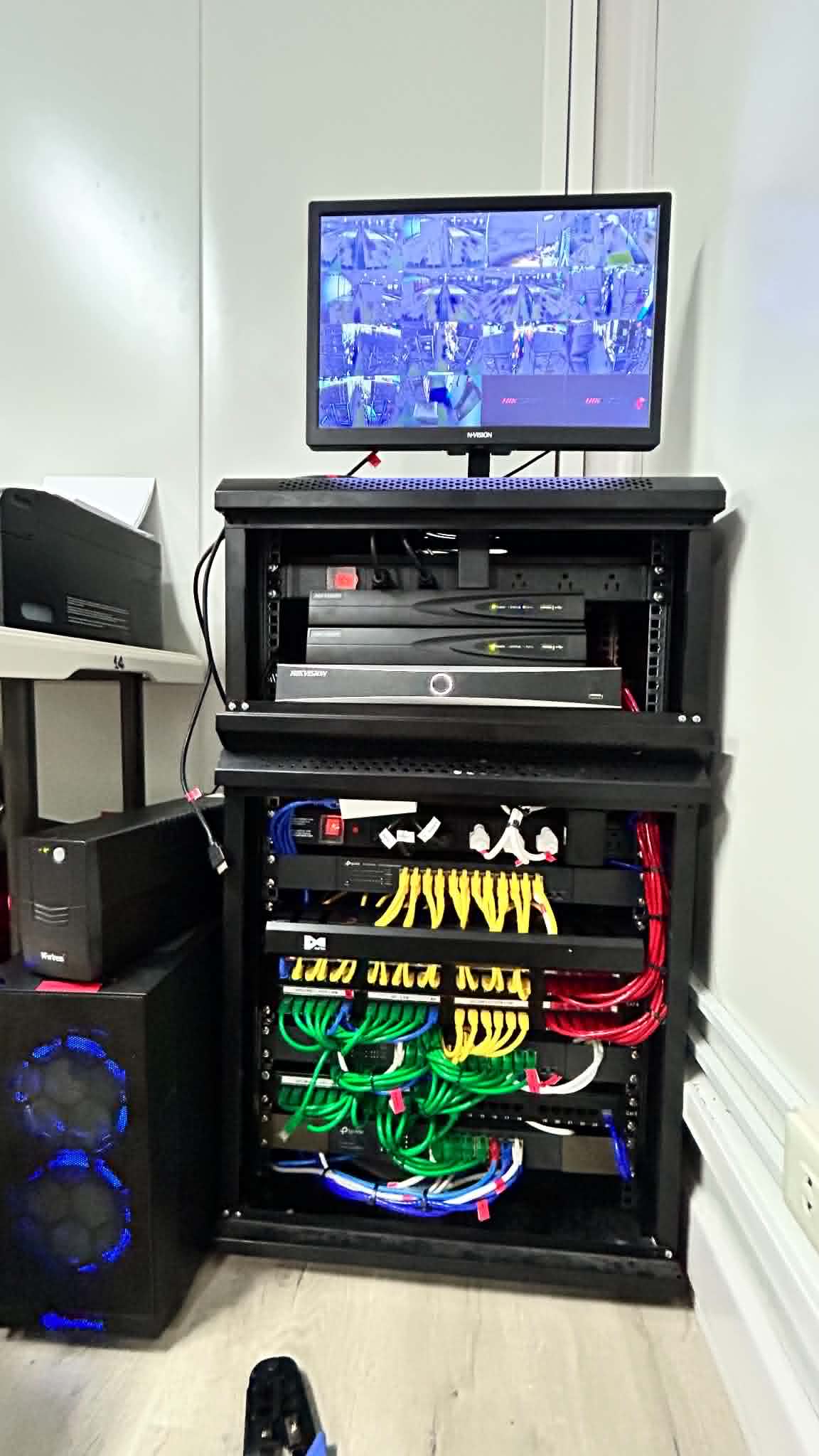 Server rack with monitoring screen, recording hardware, and organized patching inside the cabinet.