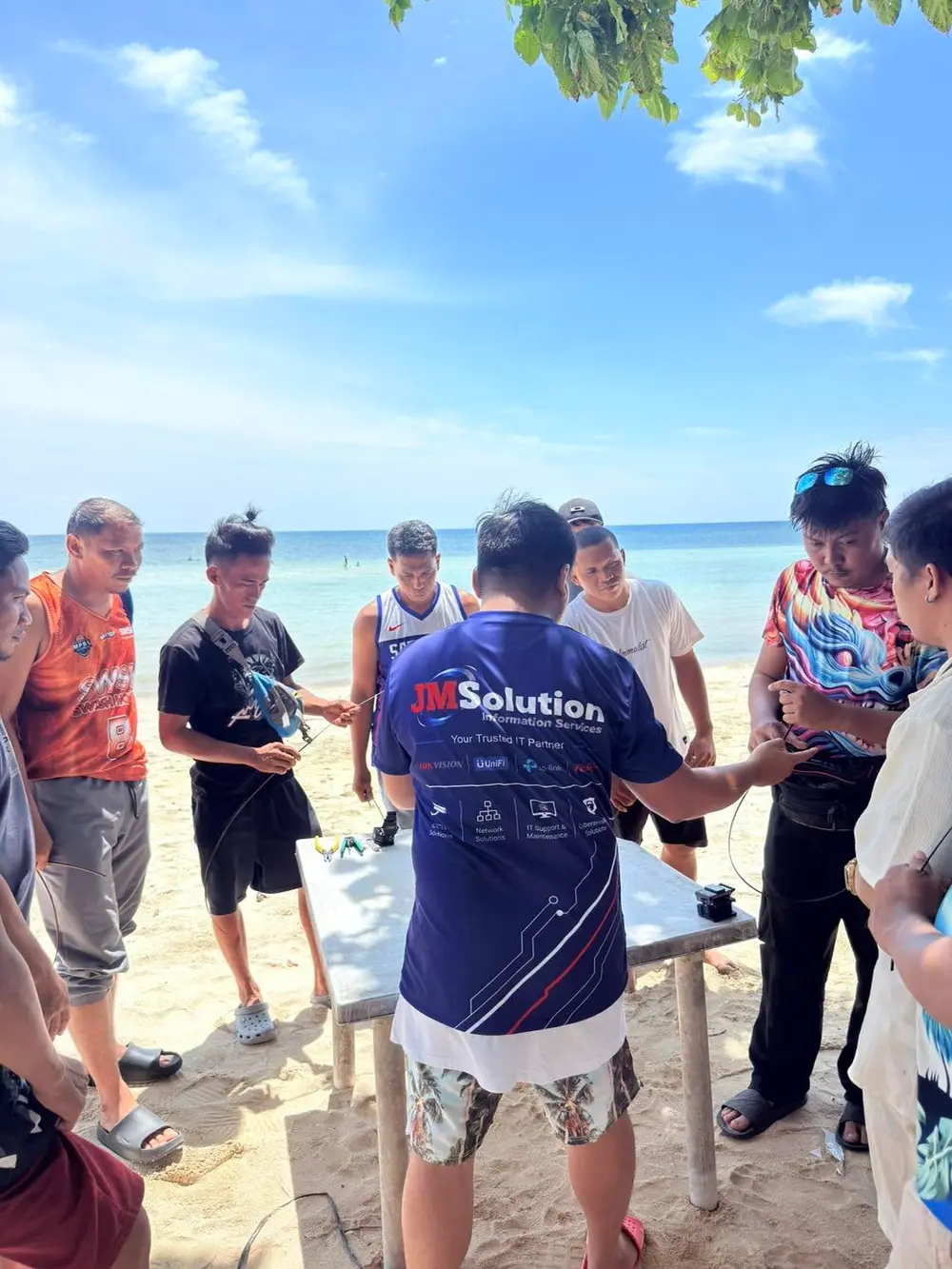 A teammate in a JM Solution shirt working together with the group on a beach activity.