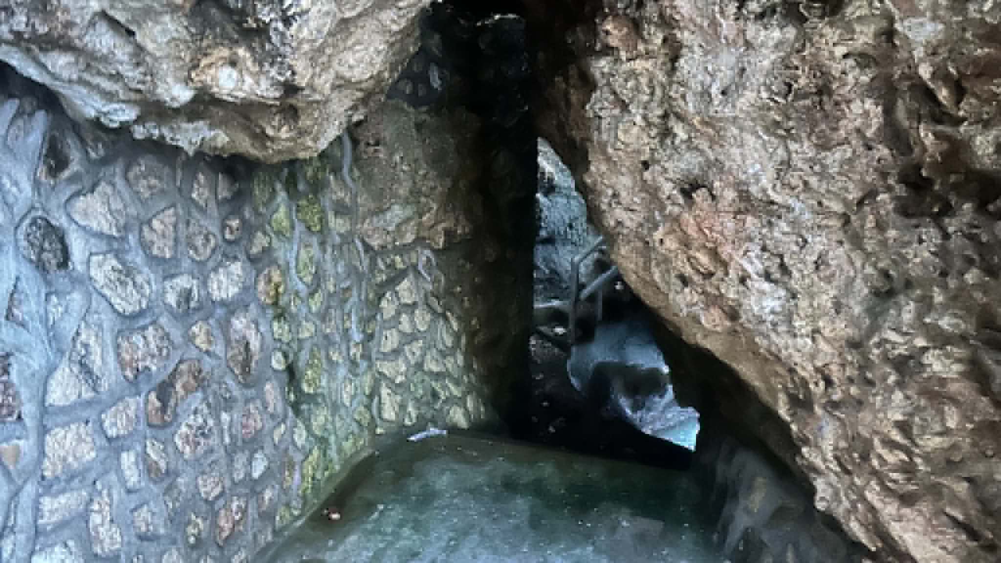 A narrow passage cut into the natural rock formation at Turtle Point, with the site's stone masonry wall along one side.